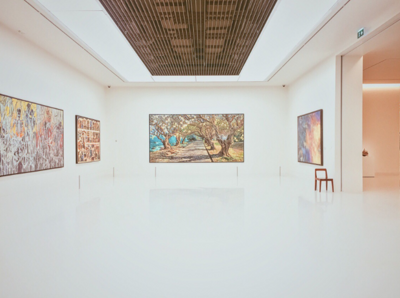 Four large pieces of art on white walls in open gallery space.